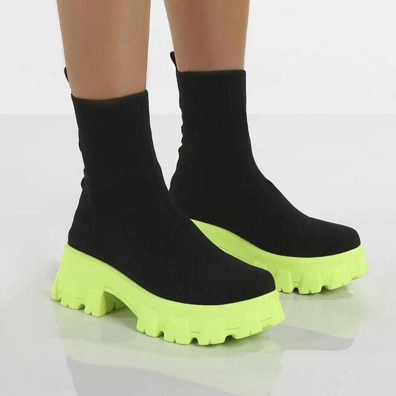 Black sock boots with neon green chunky platform soles, women's fashion footwear, trendy ankle boots, modern style, bold statement shoes.