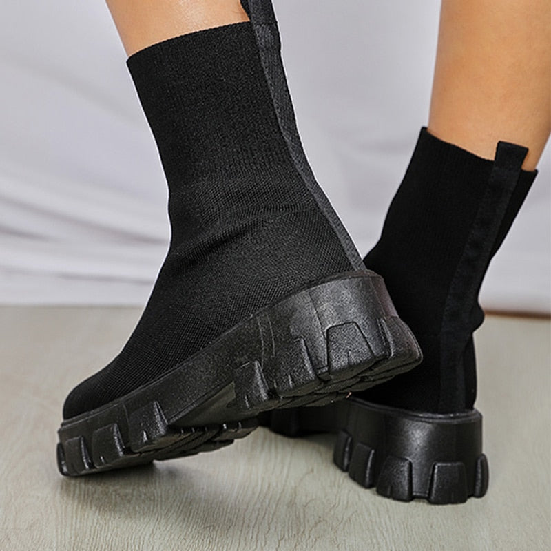 Black sock boots with chunky platform soles, featuring a sleek, modern design. Perfect for fashion-forward footwear enthusiasts seeking comfort and style.