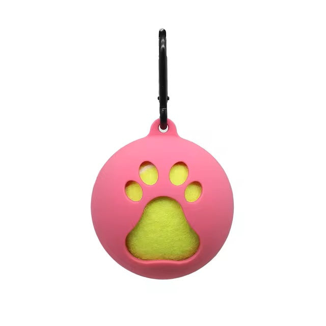 Pink silicone pet toy holder with paw-shaped cutout, featuring a yellow tennis ball inside. Includes a black carabiner for easy attachment.