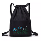 Black drawstring backpack with floral embroidery, featuring blue and white flowers. Stylish and functional bag for everyday use. Perfect for casual outings.