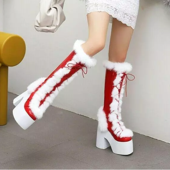 Red and white fur-trimmed knee-high boots with chunky heels, worn by a person in a white lace dress, standing indoors on a gray floor.