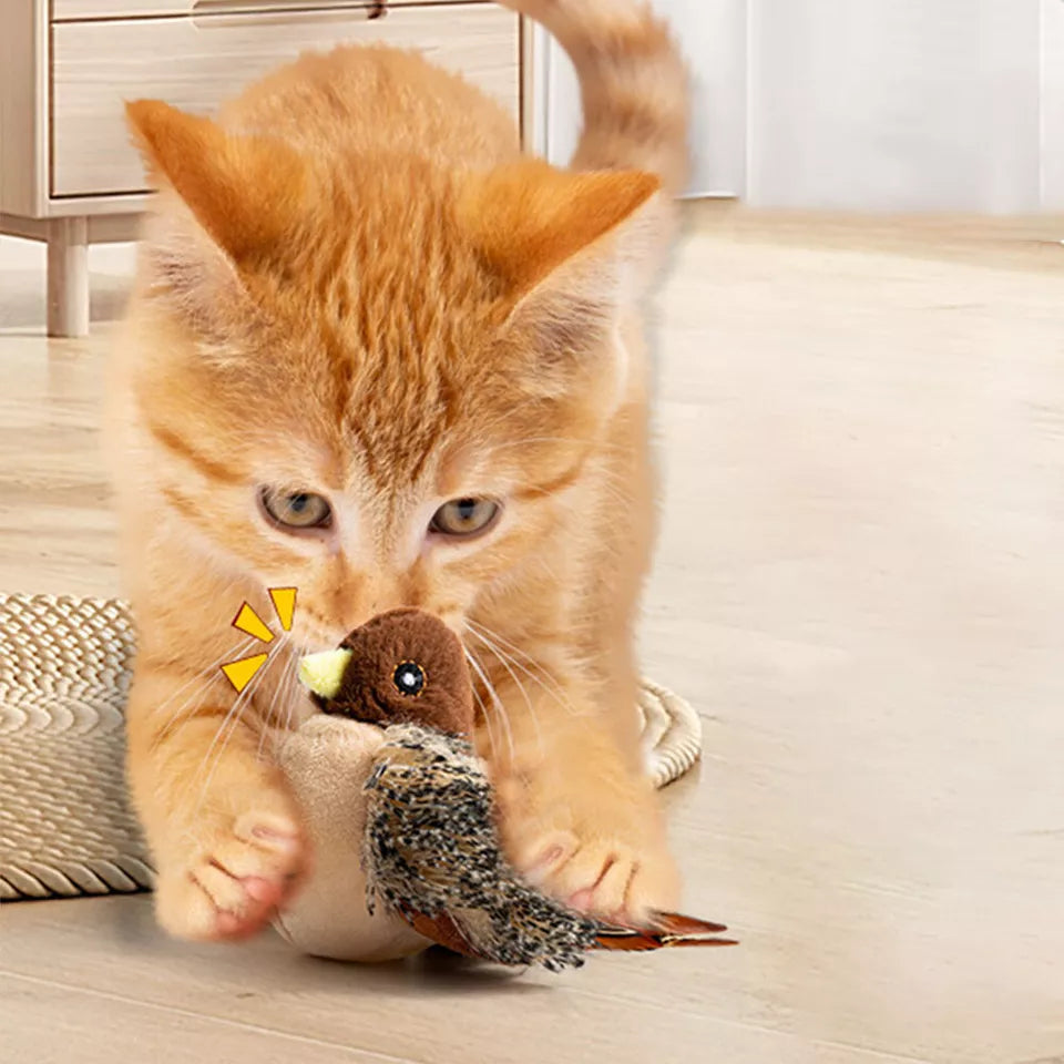 Orange kitten playing with a realistic bird toy on a wooden floor, showcasing interactive pet toys for cats. Perfect for playful indoor kittens.