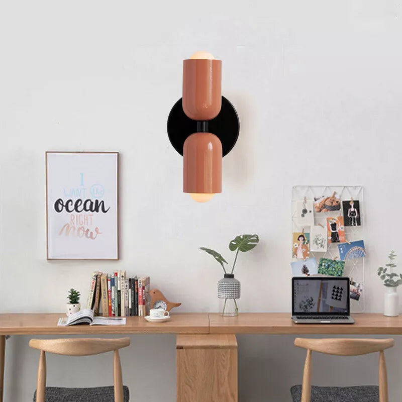 Modern wall sconce light fixture in a minimalist home office setting, featuring a sleek brown design, wooden desk, books, and decorative elements.