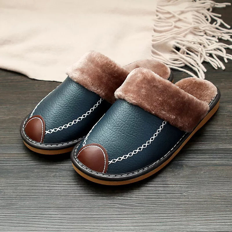 Cozy faux fur-lined navy blue slippers with brown accents on wooden floor, featuring stitched detailing, perfect for indoor comfort and warmth.