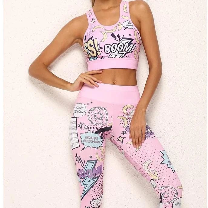 Woman wearing pink comic-style sports bra and leggings with "BOOM!" and "YES!" graphics, showcasing trendy activewear fashion.