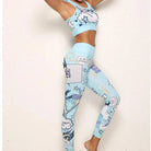 Woman wearing blue comic-style sportswear set, featuring a crop top and leggings with vibrant graphic prints, perfect for yoga or gym workouts.