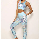 Woman wearing blue comic-style sports bra and leggings set with colorful graphics, standing against a white background. Trendy activewear fashion.