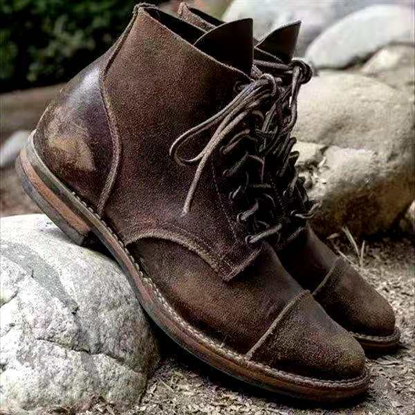 Brown leather men's lace-up boots on rocky outdoor background.