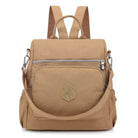 Tan waterproof nylon backpack with front zipper pocket, adjustable straps, and decorative emblem. Ideal for travel, school, or outdoor activities.