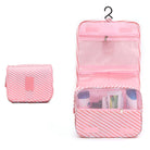 Pink travel toiletry bag with hanging hook, multiple compartments, and striped design. Ideal for organizing cosmetics and toiletries on the go.