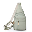 Sage green leather crossbody sling bag with adjustable patterned strap, multiple zippered pockets, and gold-tone hardware. Stylish and functional accessory.