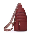 Stylish maroon leather crossbody bag with adjustable patterned strap, featuring multiple zippered compartments. Perfect for travel and daily use.