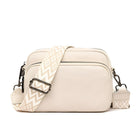 Cream leather crossbody bag with geometric strap, front zip pocket, and adjustable buckle. Stylish women's accessory for casual and formal wear.