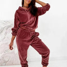Woman wearing a stylish red velour tracksuit set, featuring a hoodie and jogger pants. Perfect for casual wear, comfortable and trendy fashion.