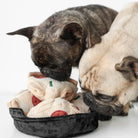 Two French Bulldogs sniffing a plush deep dish pizza toy with pepperoni and vegetable toppings, perfect for dog playtime.