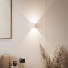 Modern minimalist wall sconce in a neutral-toned living room, featuring geometric design and soft ambient lighting. Ideal for contemporary home decor.