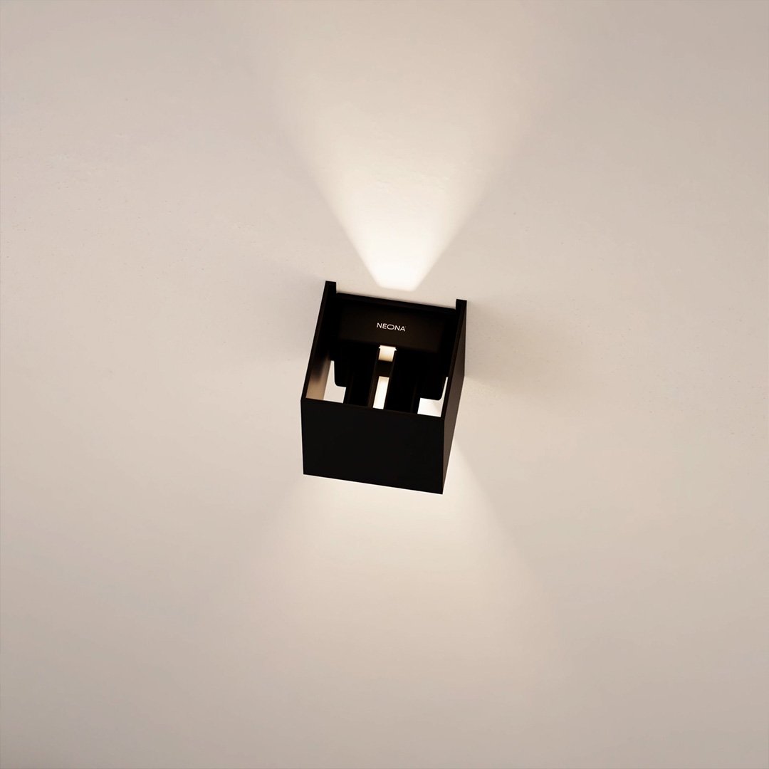 Modern black wall sconce with geometric design, illuminating a white wall. Contemporary lighting fixture, minimalist home decor, LED wall light.